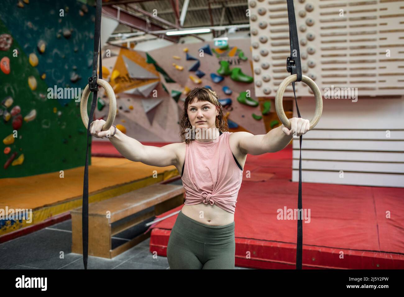 Determined young woman at gymnastics rings in climbing center Stock
