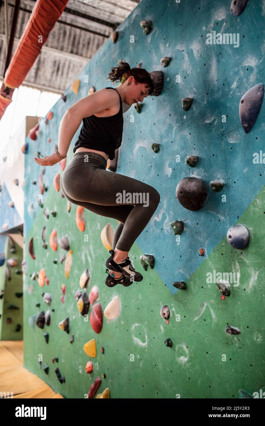 Young woman jumping off climbing wall Stock Photo - Alamy