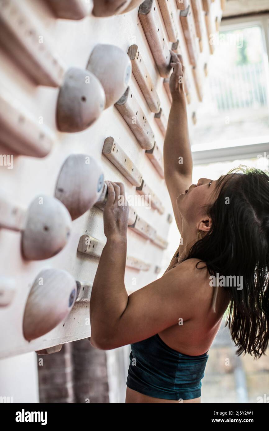 Woman hanging from climbing board in climbing center Stock Photo
