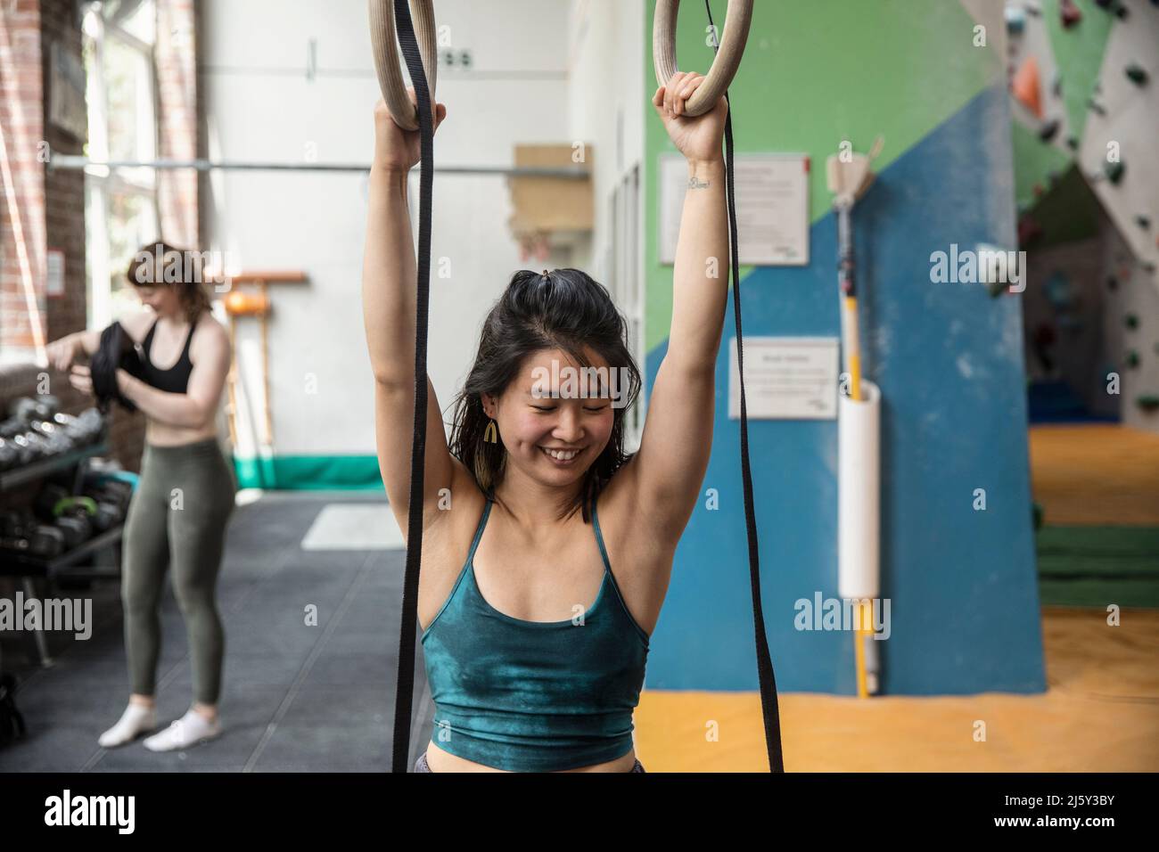 Happy woman exercising at gymnastics rings in gym Stock Photo
