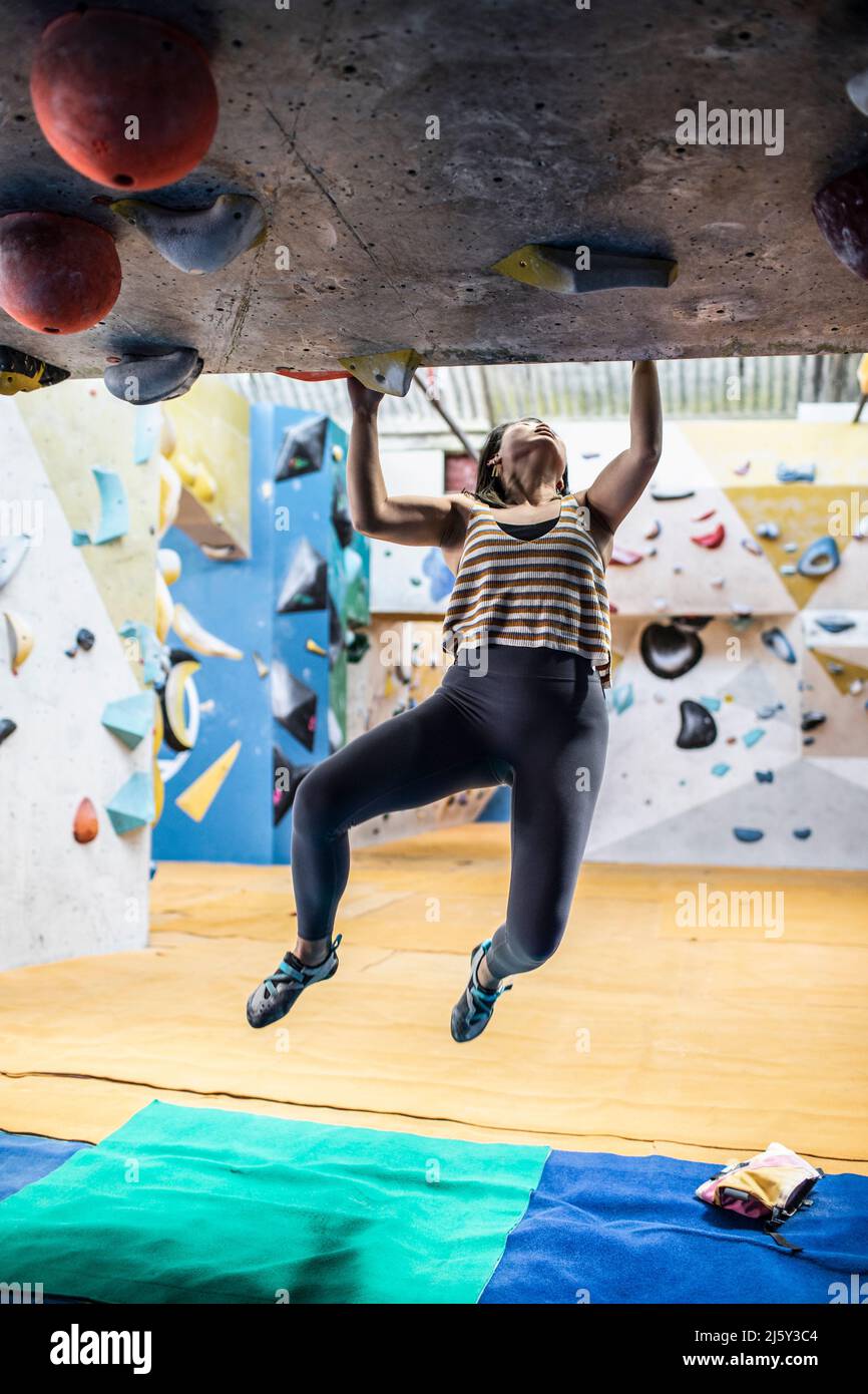 Female rock climber hanging from climbing wall Stock Photo