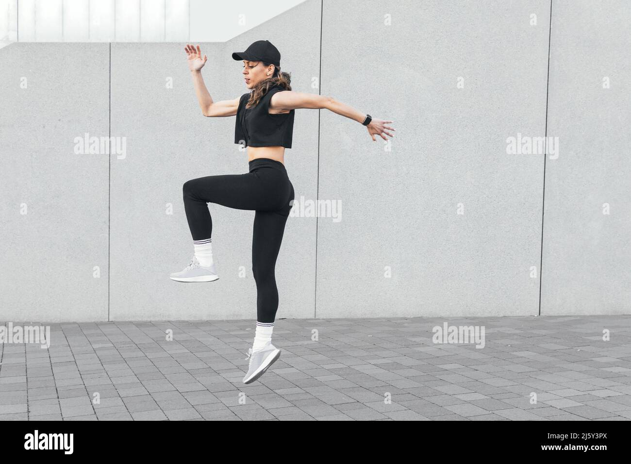 Full body side view of slim athletic female in sportswear jumping on