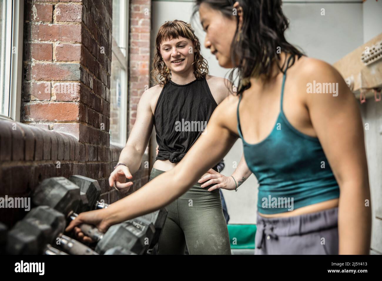 Women friends working out with dumbbells in gym Stock Photo