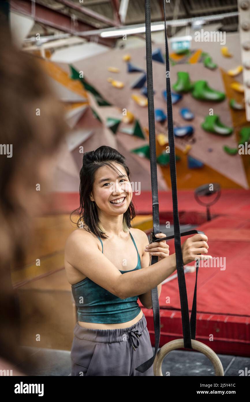 Smiling woman exercising at gymnastics rings in climbing gym Stock Photo