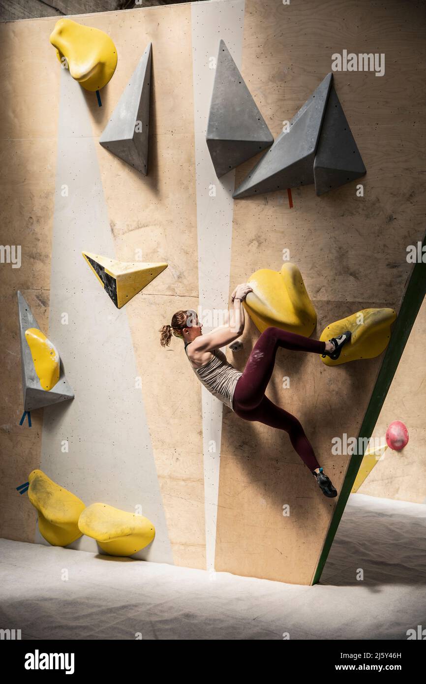 Young female rock climber hanging from climbing wall Stock Photo
