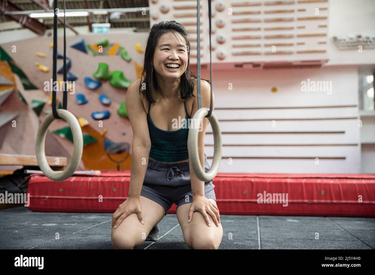 Portrait happy female rock climber training in climbing gym Stock Photo