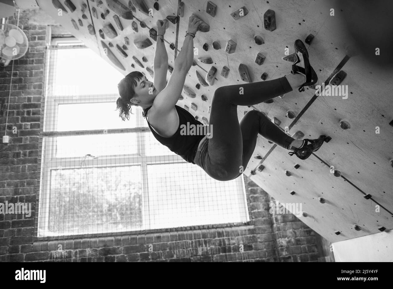 Young woman hanging from climbing wall Stock Photo