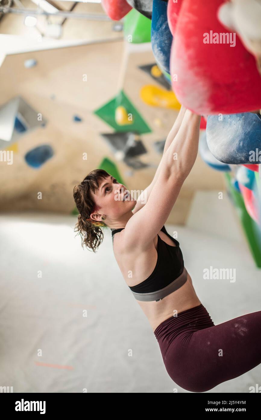 Young female rock climber hanging from climbing wall Stock Photo