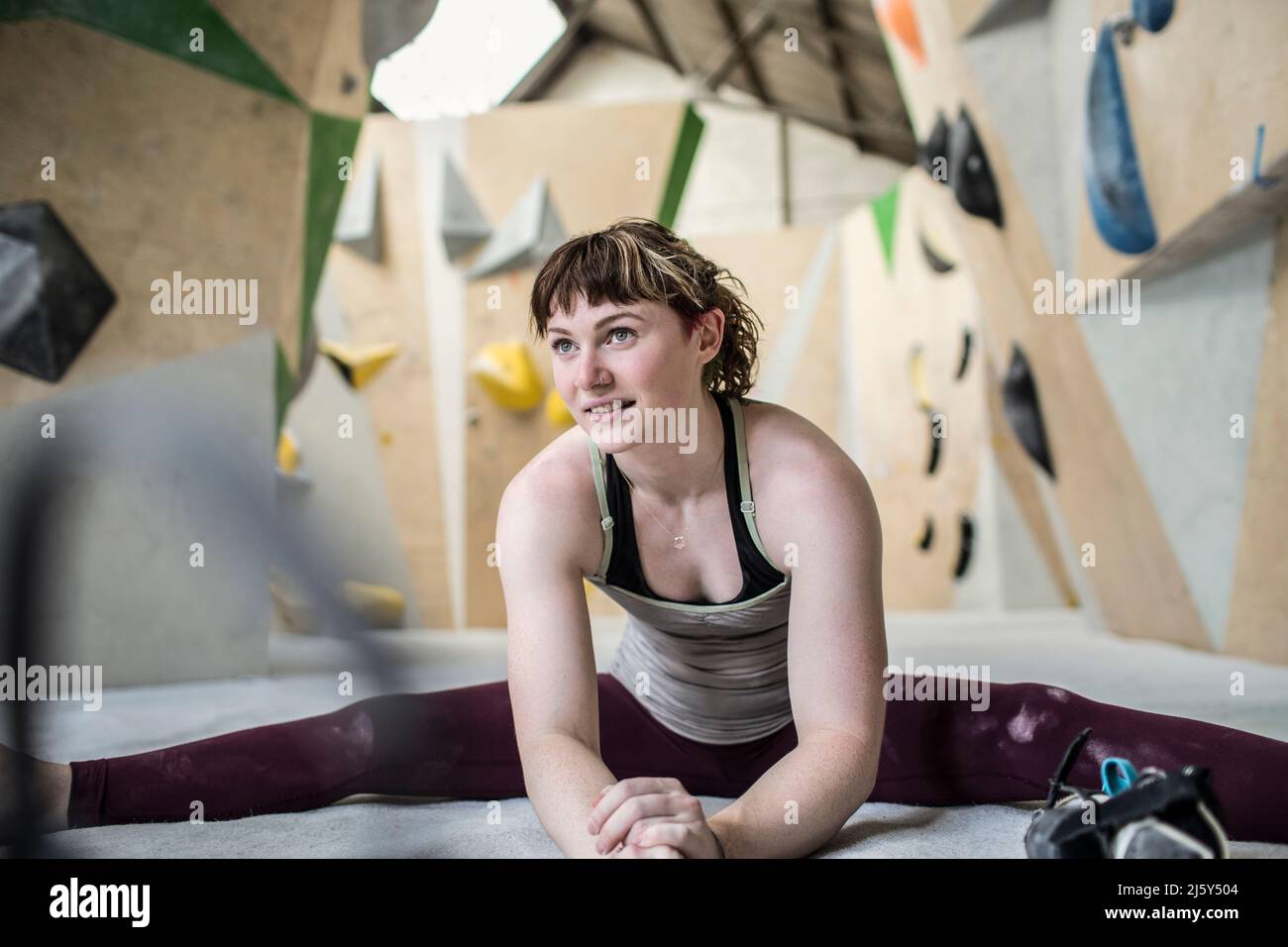 Young female rock climber stretching in climbing gym Stock Photo
