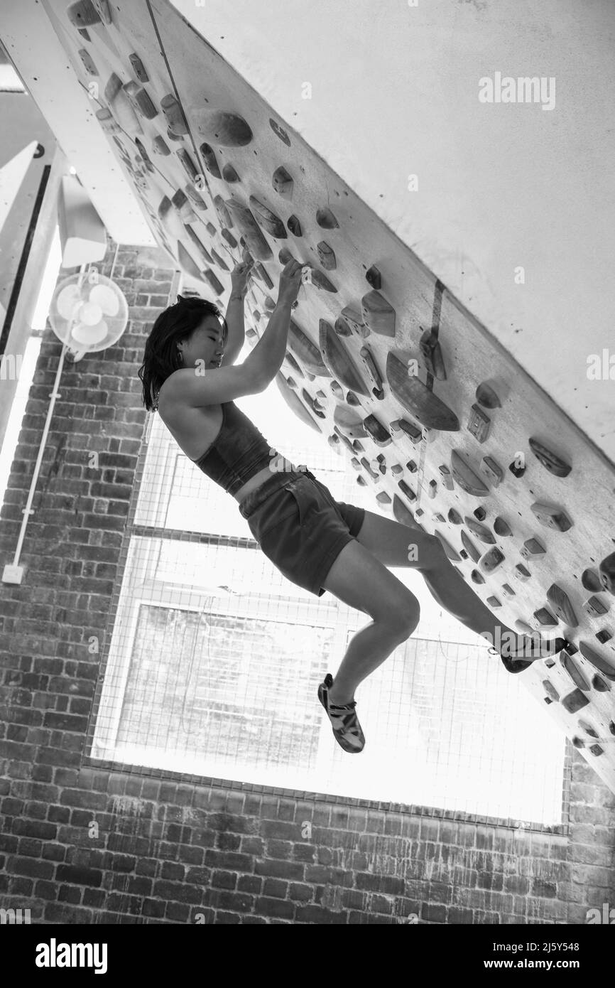 Female rock climber hanging from climbing wall in gym Stock Photo