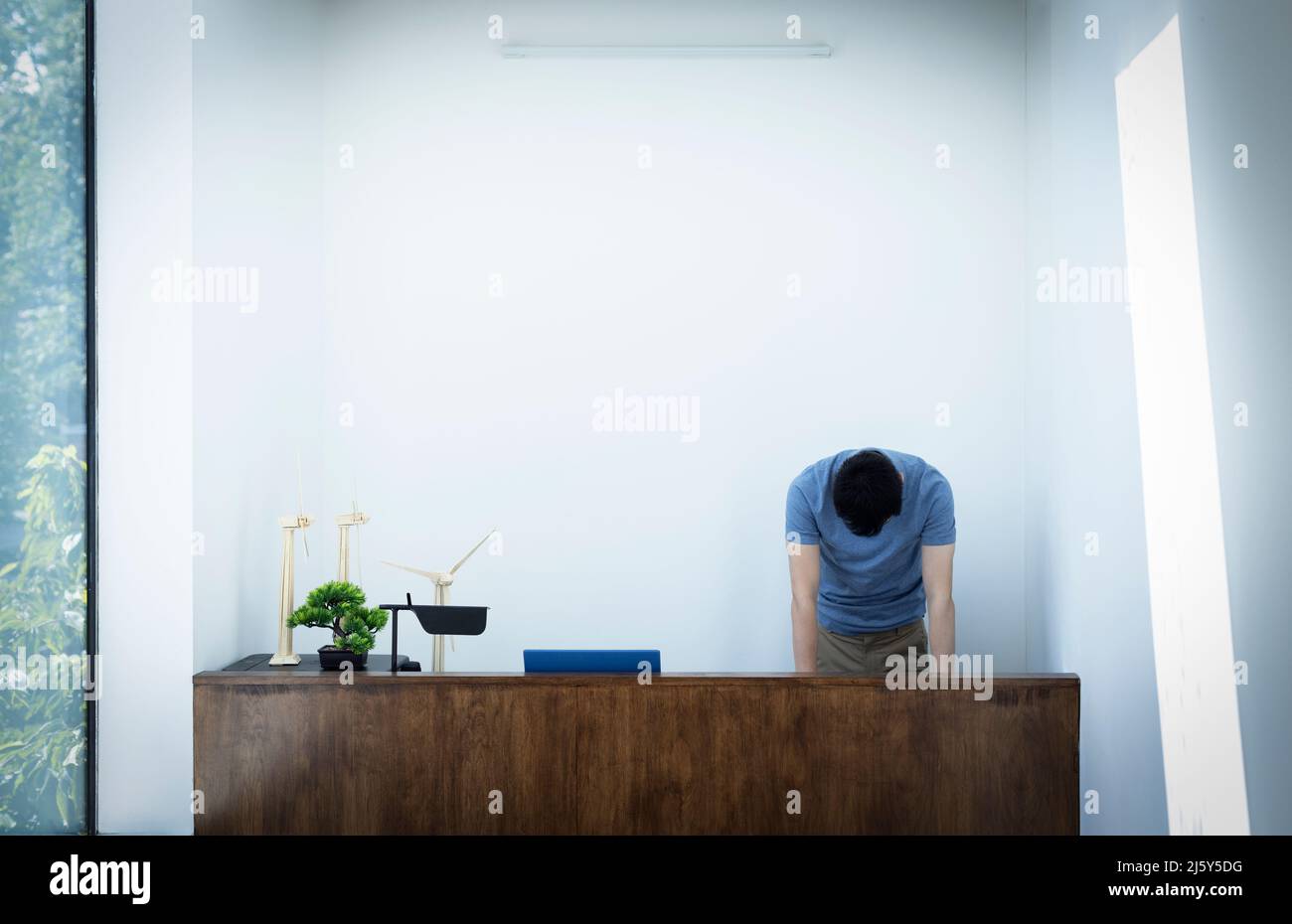 Male engineer with head down at desk with wind turbine models Stock Photo Alamy