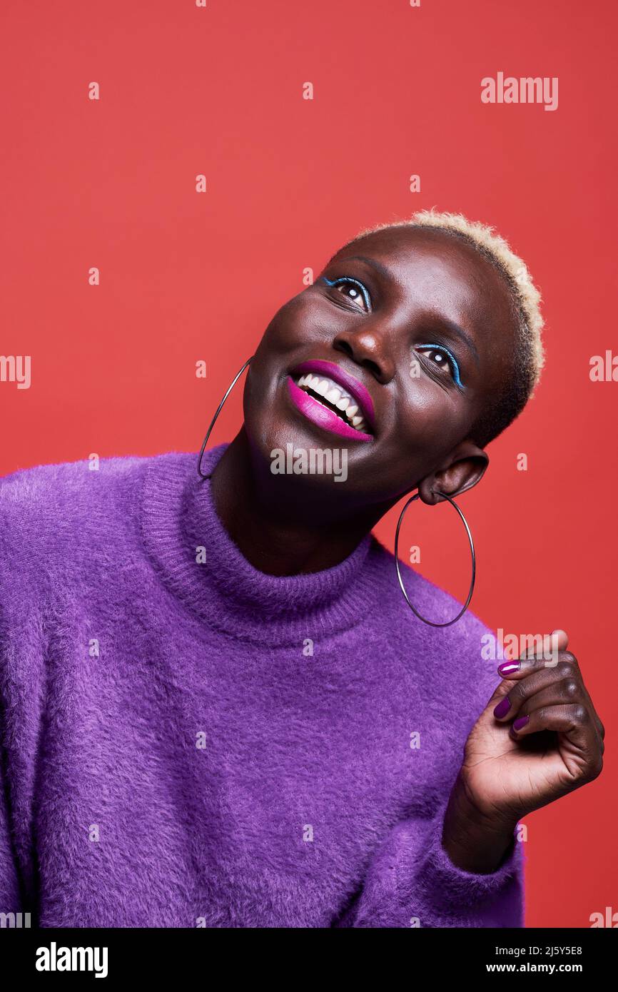Portrait of African female in pink wear while standing on red background in studio Stock Photo