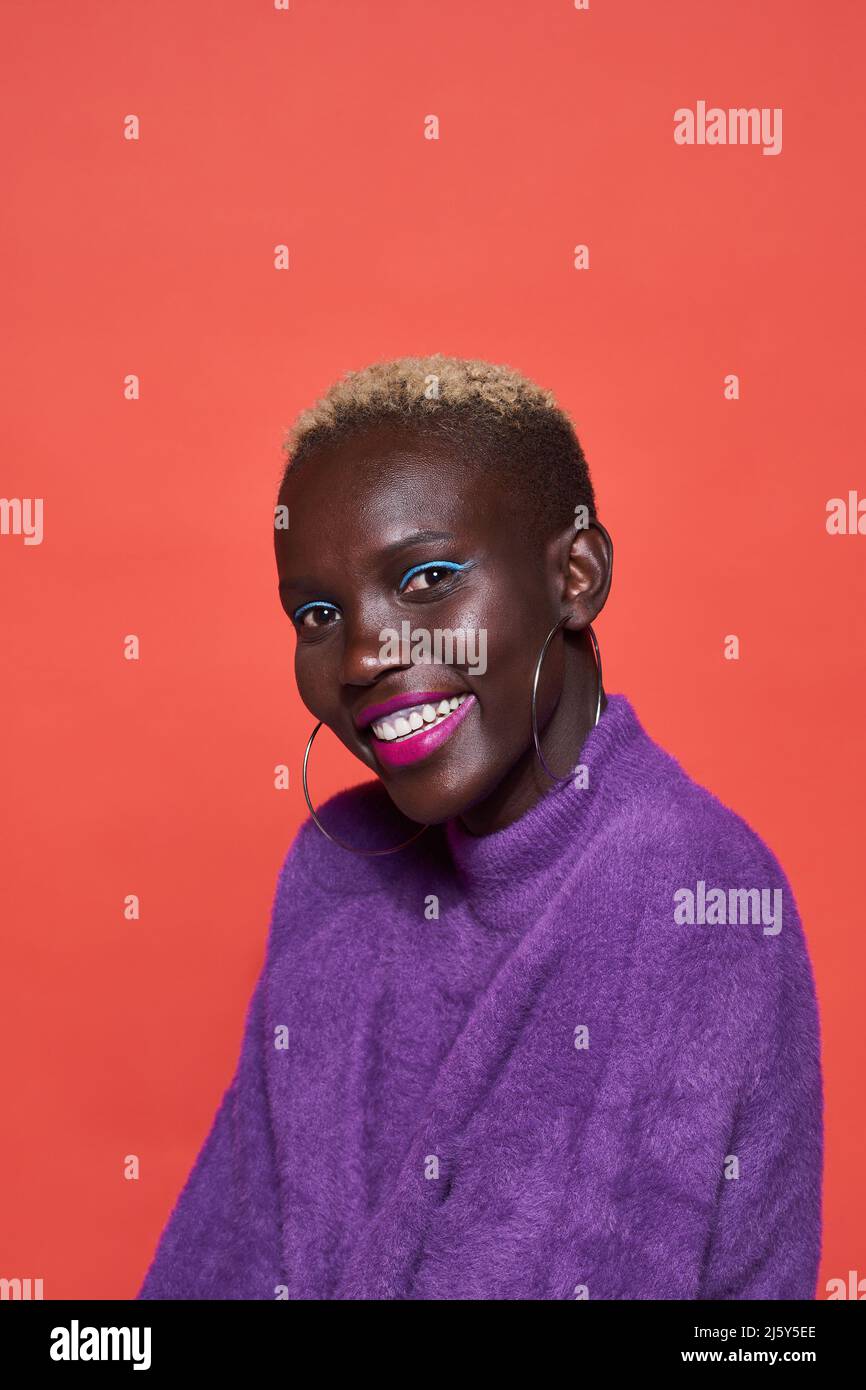 Portrait of African female in pink wear while standing on red background in studio Stock Photo