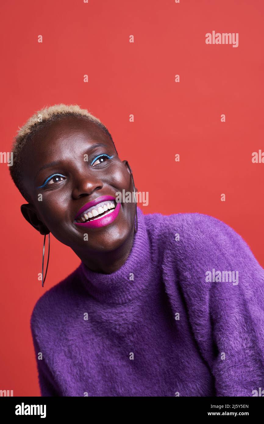 Portrait of African female in pink wear while standing on red background in studio Stock Photo