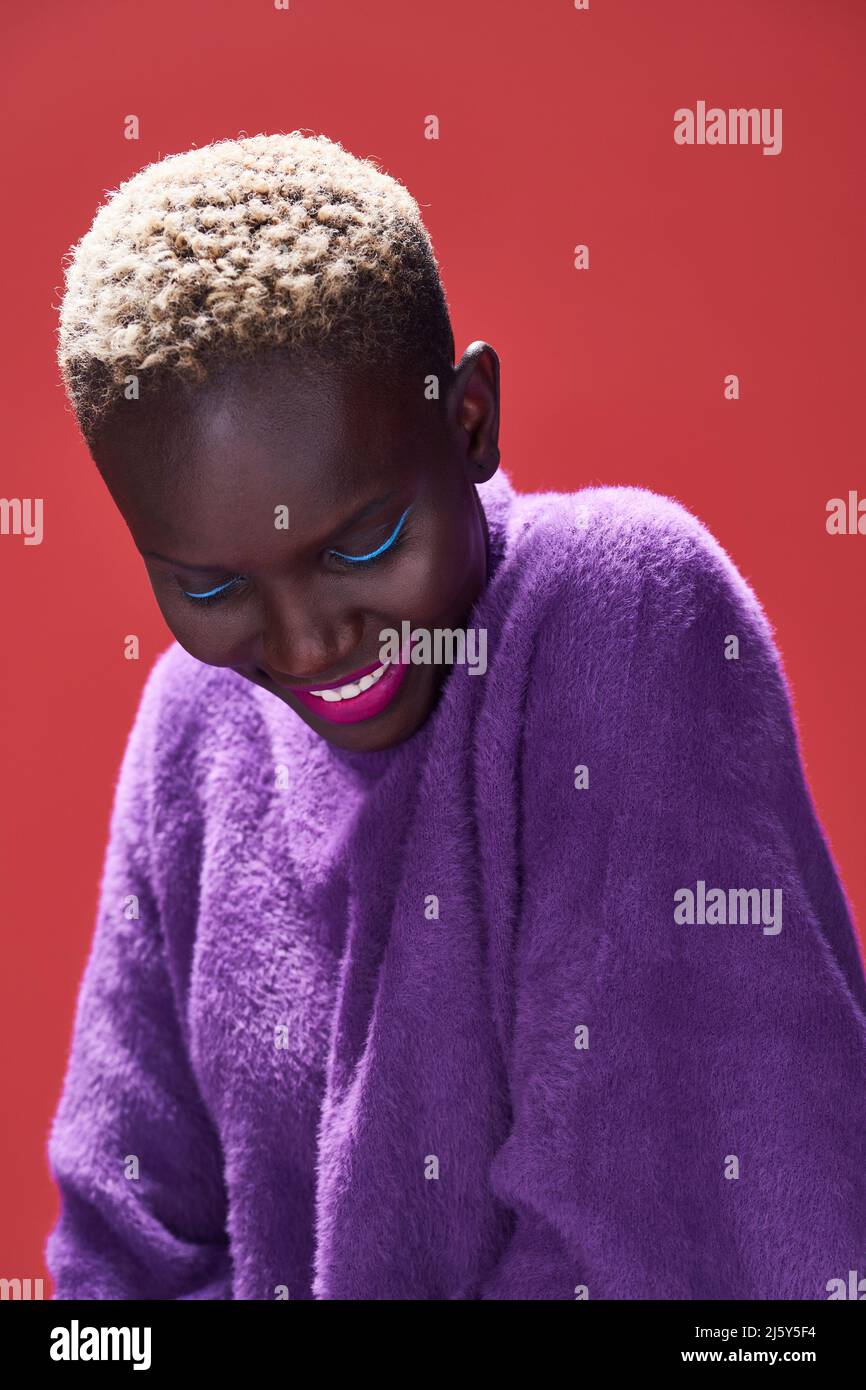 Close-up of a cheerful African Woman with short hair in a studio shot with a red background Stock Photo