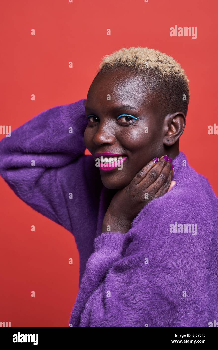 Close-up of a cheerful African Woman with short hair in a studio shot with a red background Stock Photo