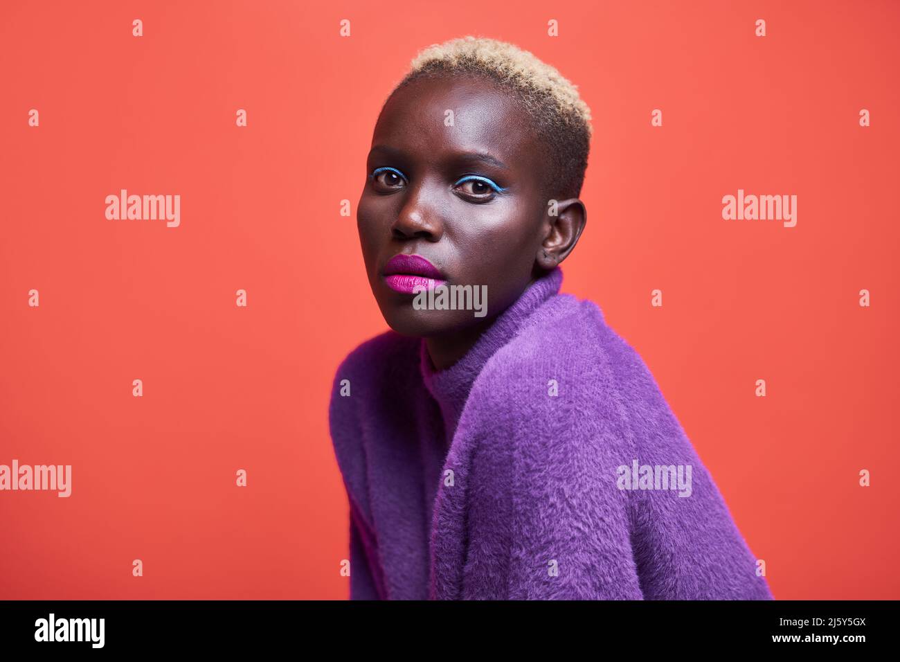 Portrait of a young African-American Woman looking at the camera on a red background Stock Photo
