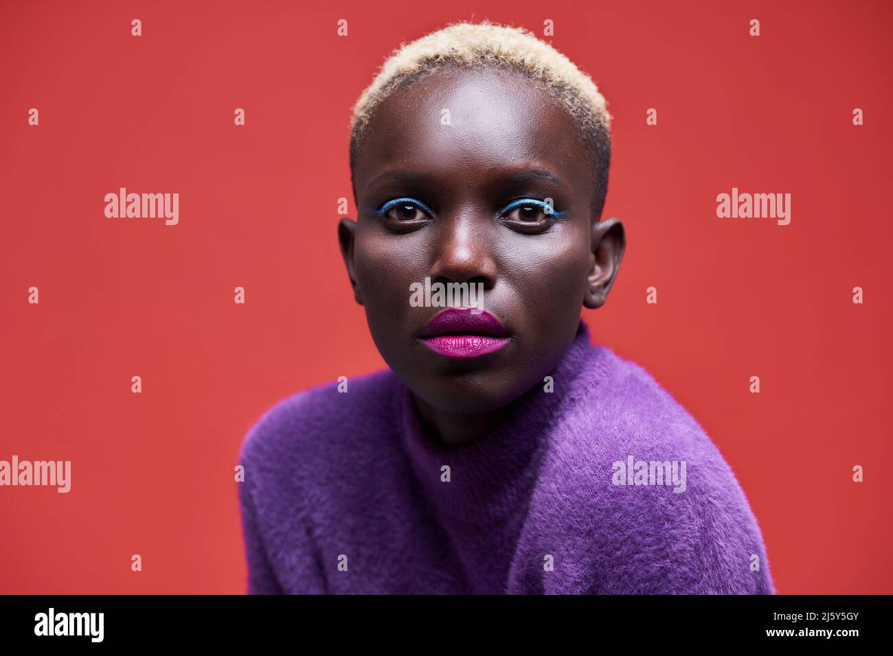 Portrait of a young African-American Woman looking at the camera on a red background Stock Photo