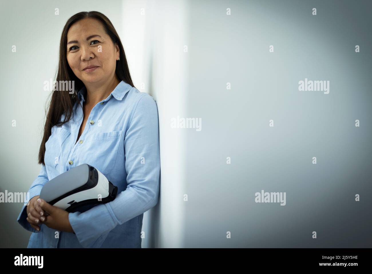 Portrait confident mature woman holding VR headset Stock Photo