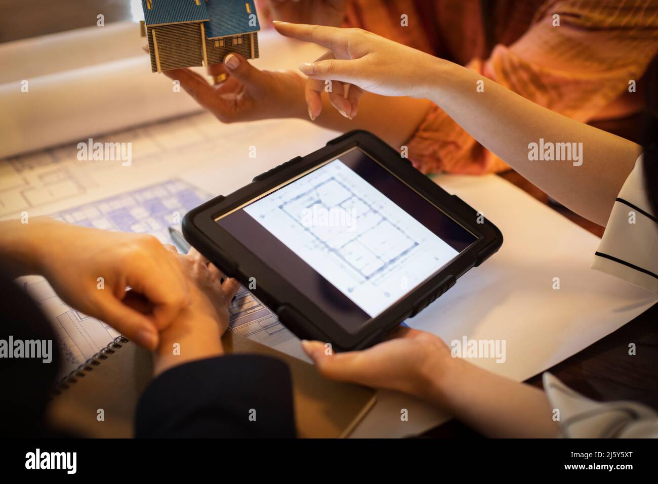 Close up architects with digital tablet discussing blueprints Stock Photo