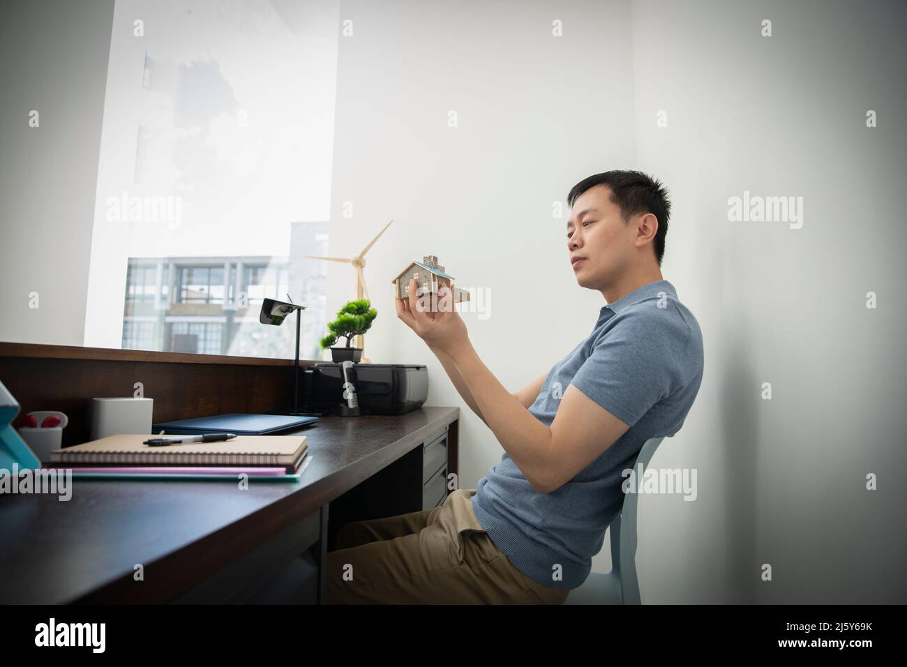 Male engineer looking at house model at office desk Stock Photo