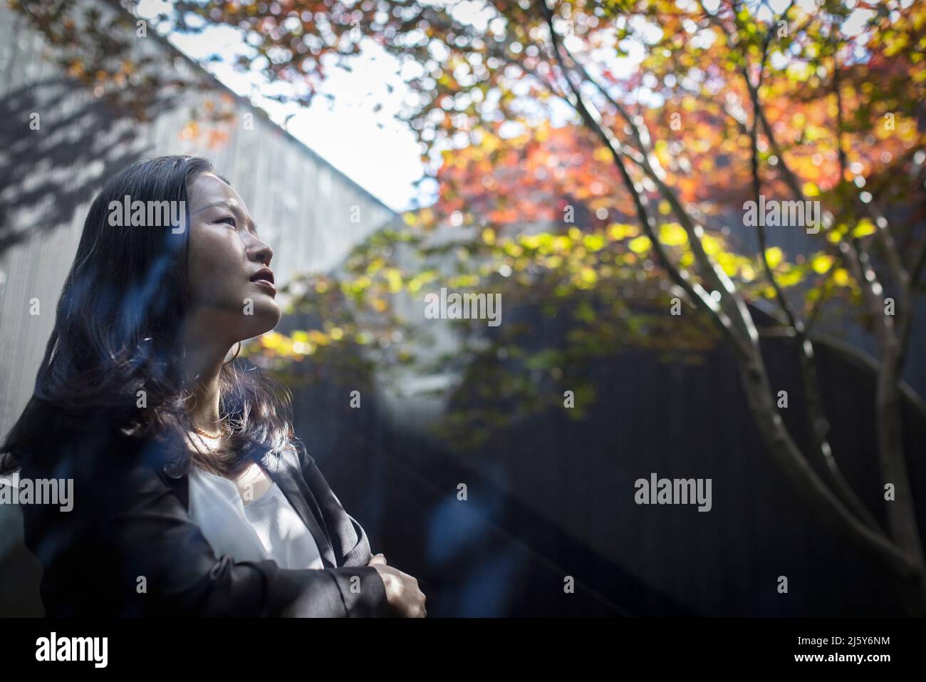 Thoughtful young woman looking up in courtyard Stock Photo