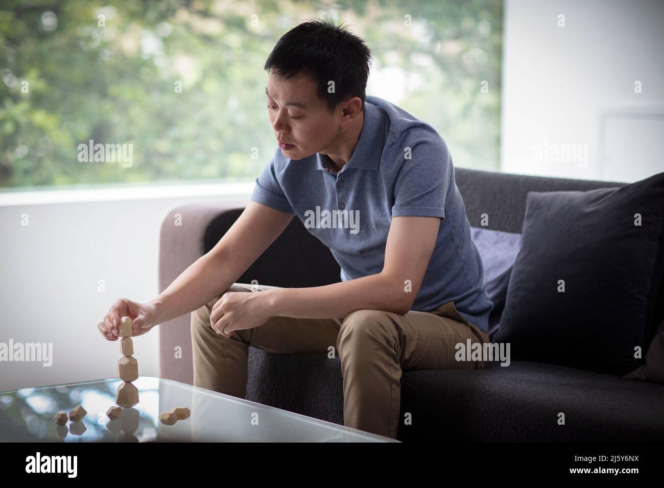 Man stacking wood pieces at coffee table in living room Stock Photo