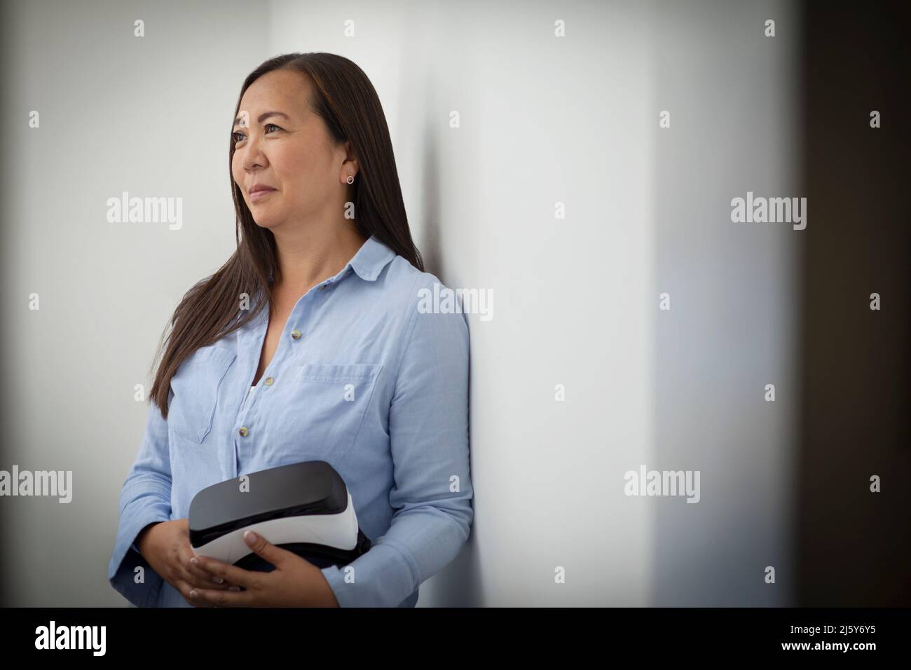 Smiling mature businesswoman holding VR headset Stock Photo