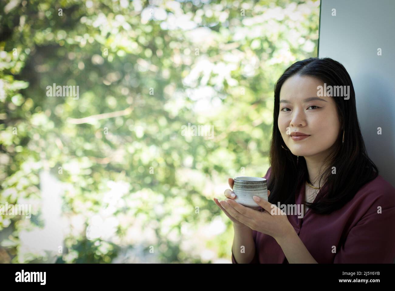 Portrait young woman drinking tea in window Stock Photo