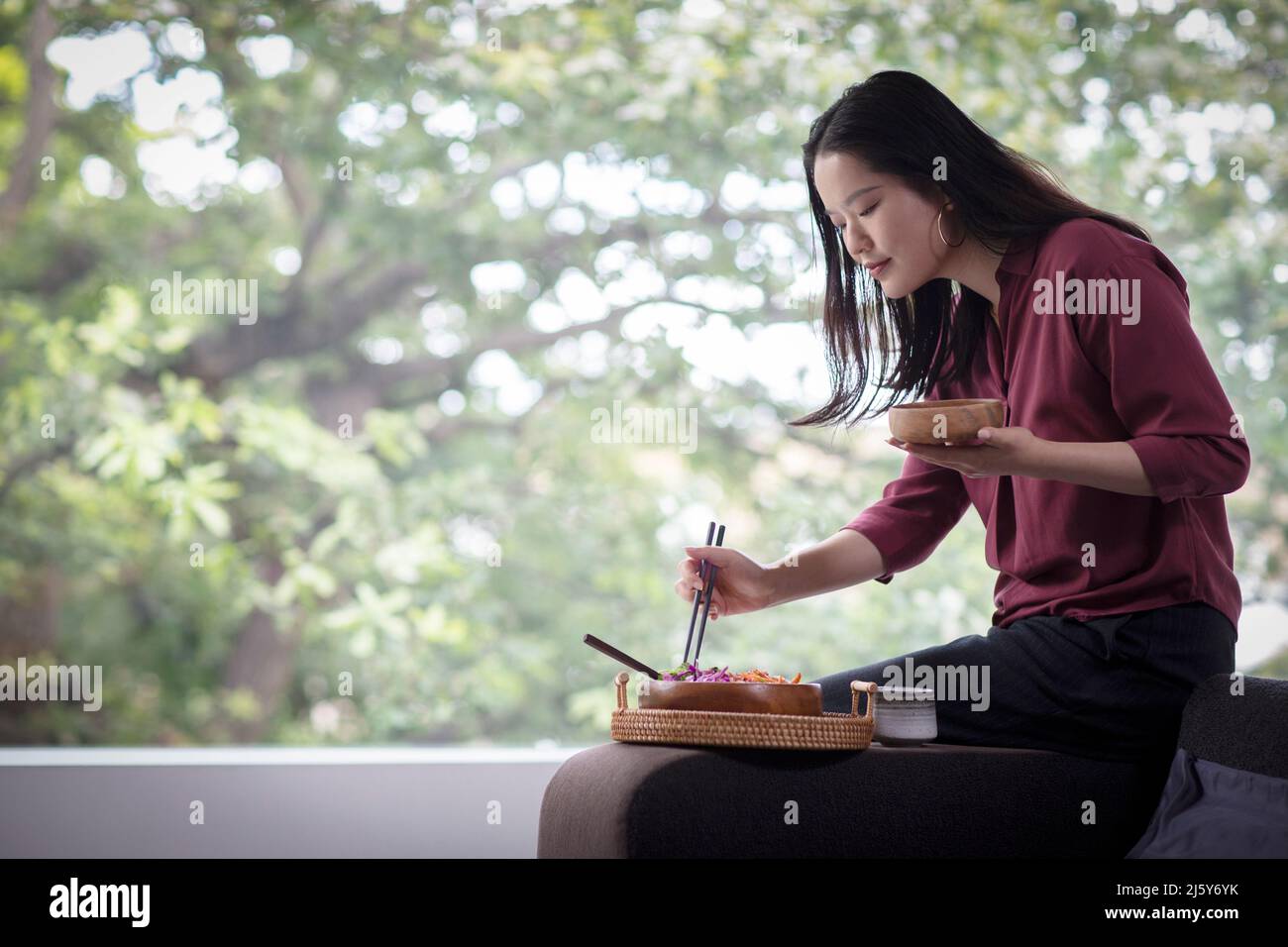 Young woman eating lunch with chopsticks at home Stock Photo