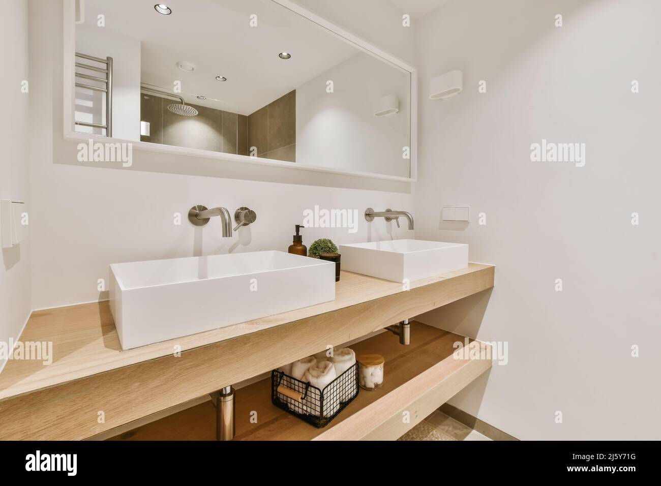 Bathroom with mirror and white ceramic sink near skincare supplies at ...