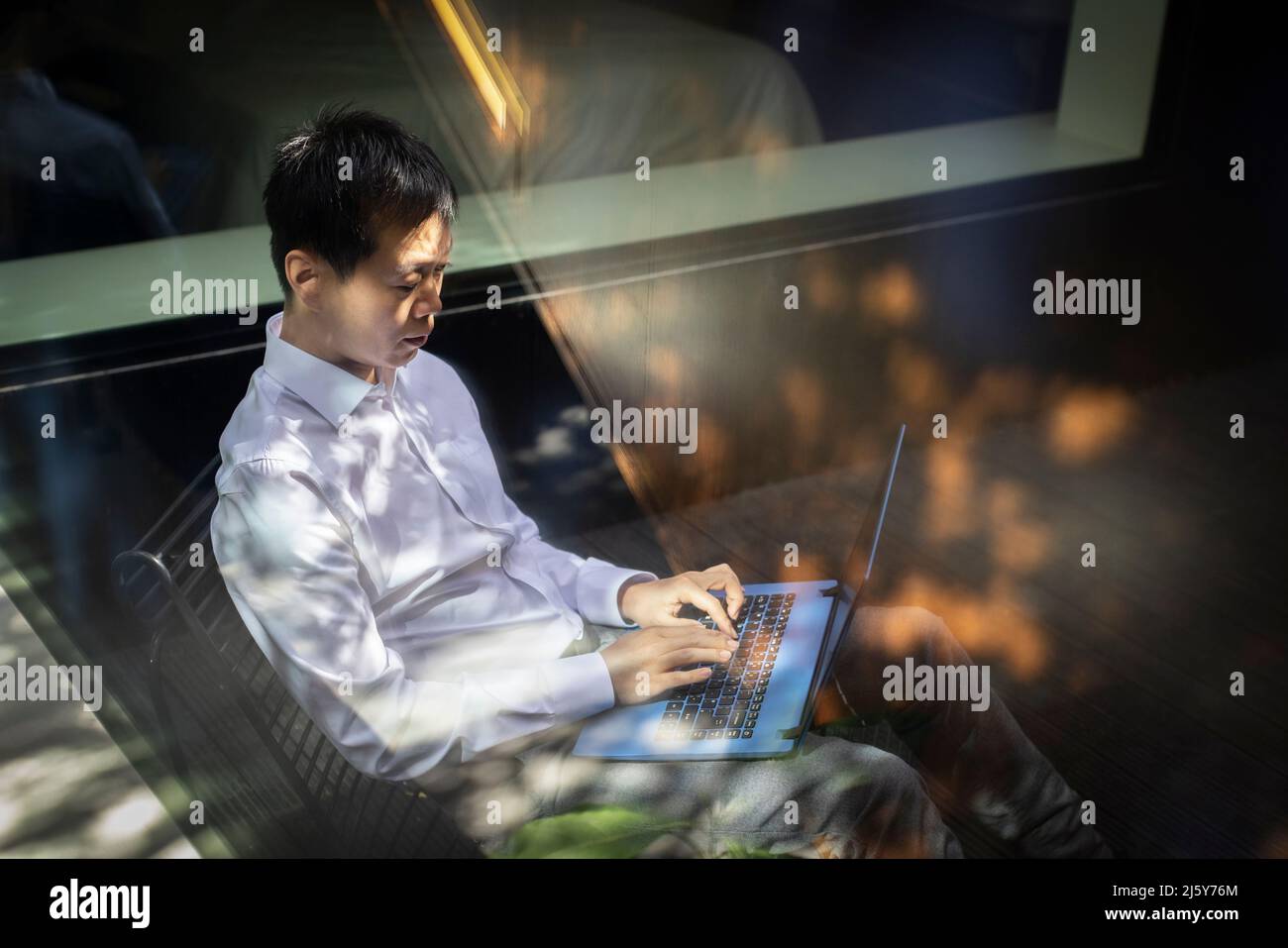 Businessman working at laptop on sunny patio Stock Photo
