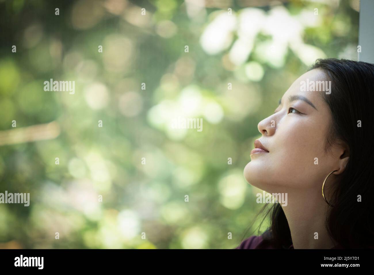 Profile serene young woman looking out window Stock Photo