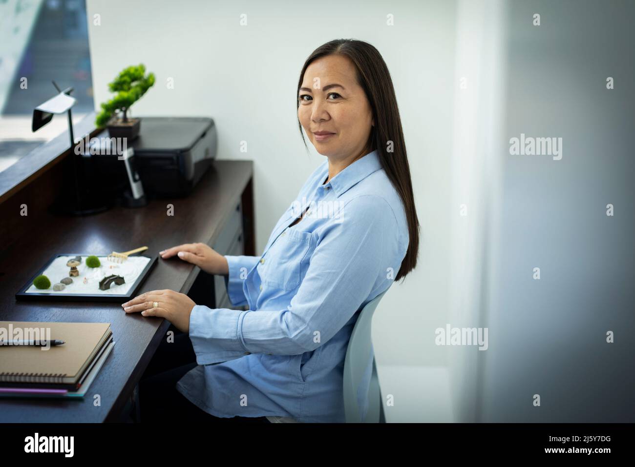 Portrait businesswoman with zen garden in office Stock Photo