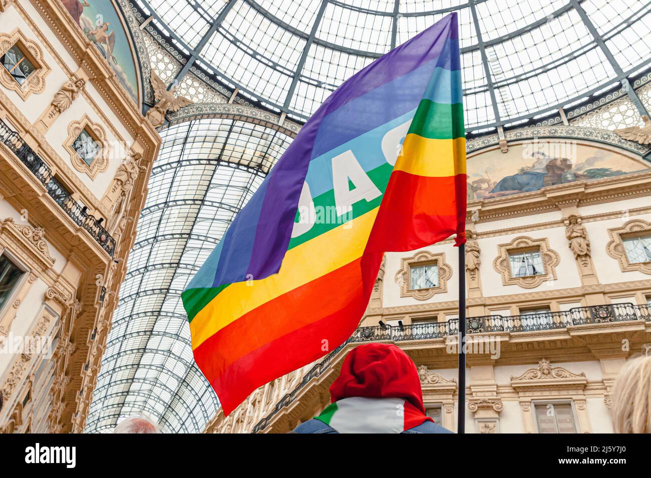 A peace activist holds a rainbow flag during a pacifist demonstration against fascism and the Russia-Ukraine war. Peace flag in Milan, Italy Stock Photo
