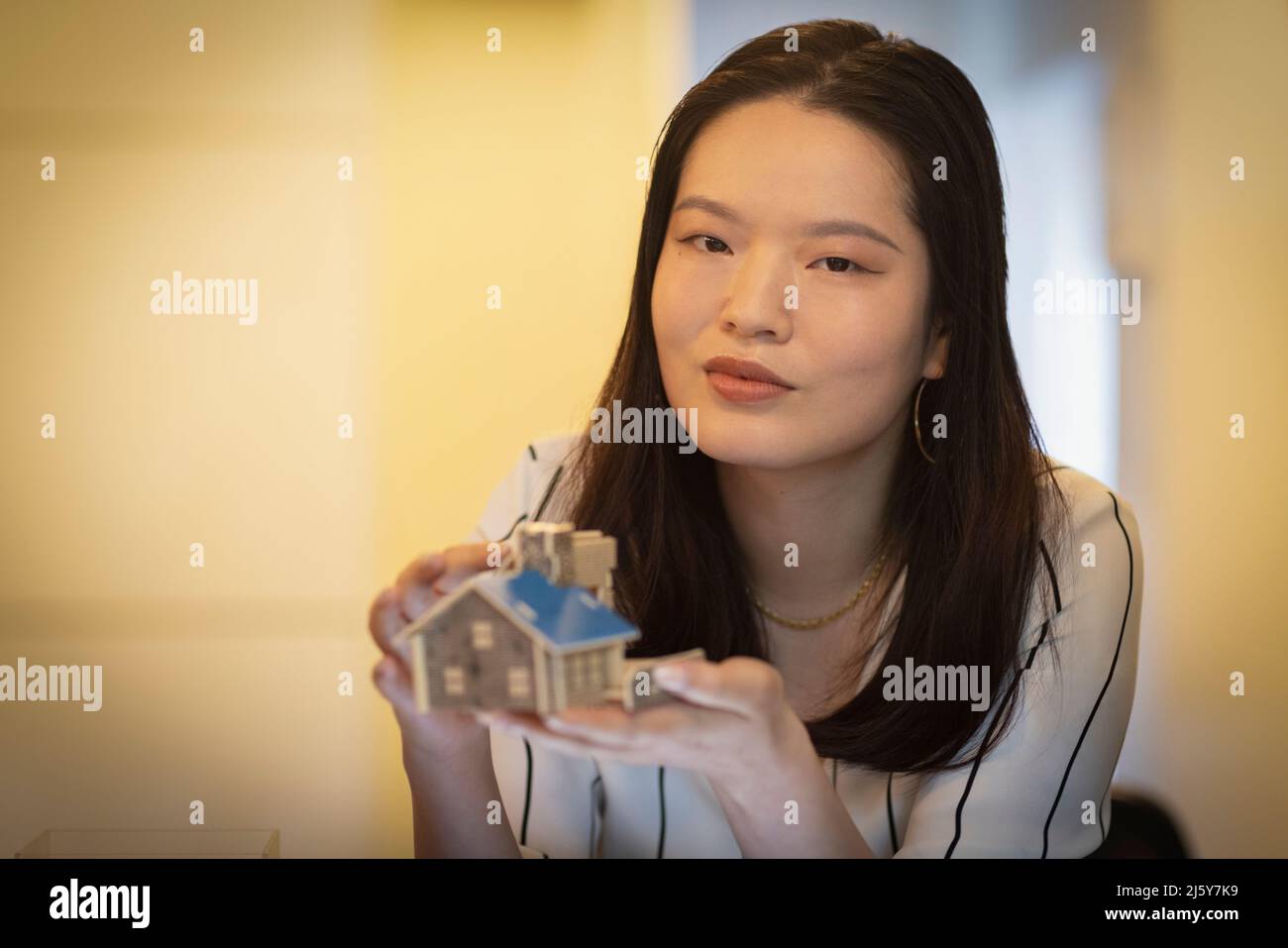Portrait confident female architect holding tiny house model Stock Photo