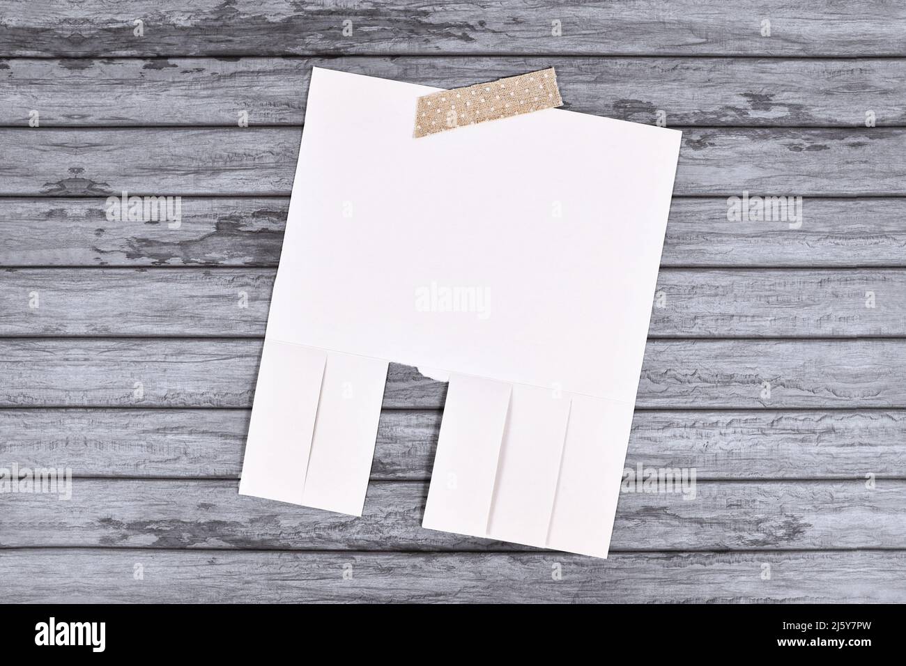 Empty white tear-off stub paper note without text on wooden wall Stock Photo