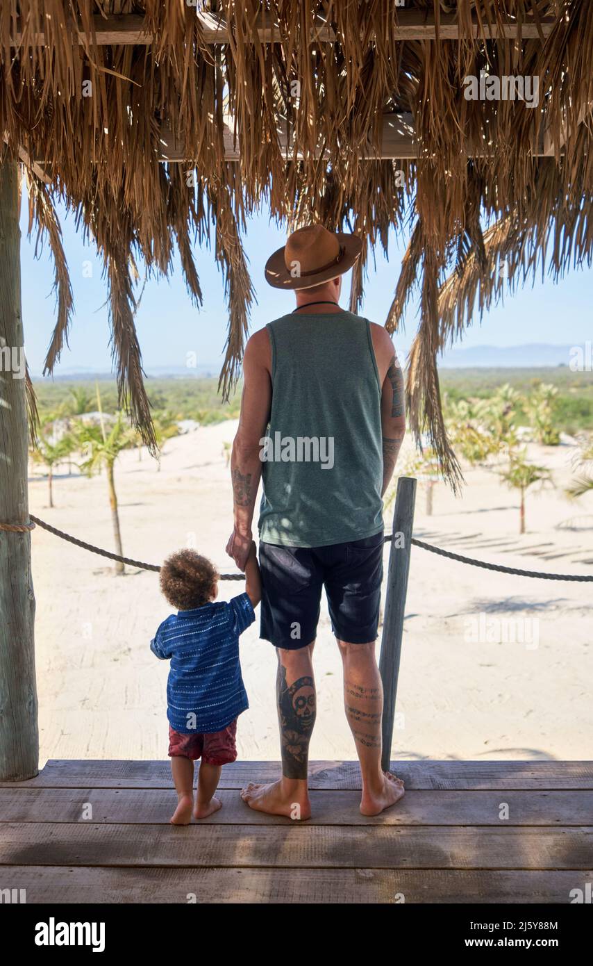 Father and toddler son holding hands in summer beach hut Stock Photo