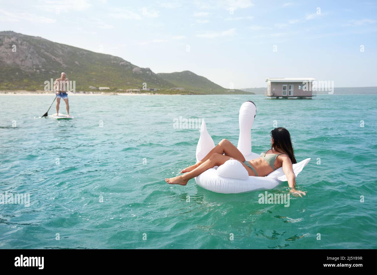 Couple on inflatable swan and paddle board on summer ocean Stock Photo