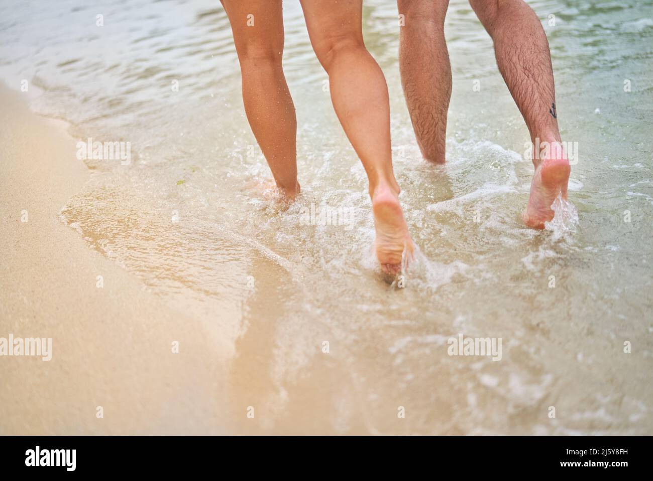 Legs of couple running in ocean surf Stock Photo