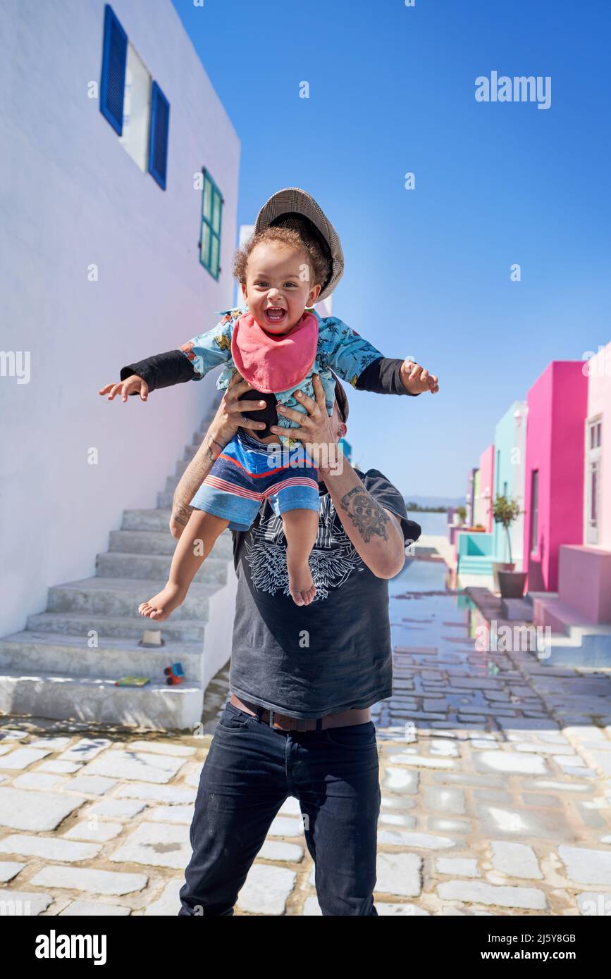 Portrait father holding cute, carefree toddler boy on sunny street Stock Photo