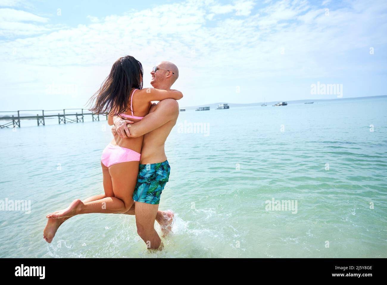 Happy, carefree couple playing in sunny summer ocean Stock Photo