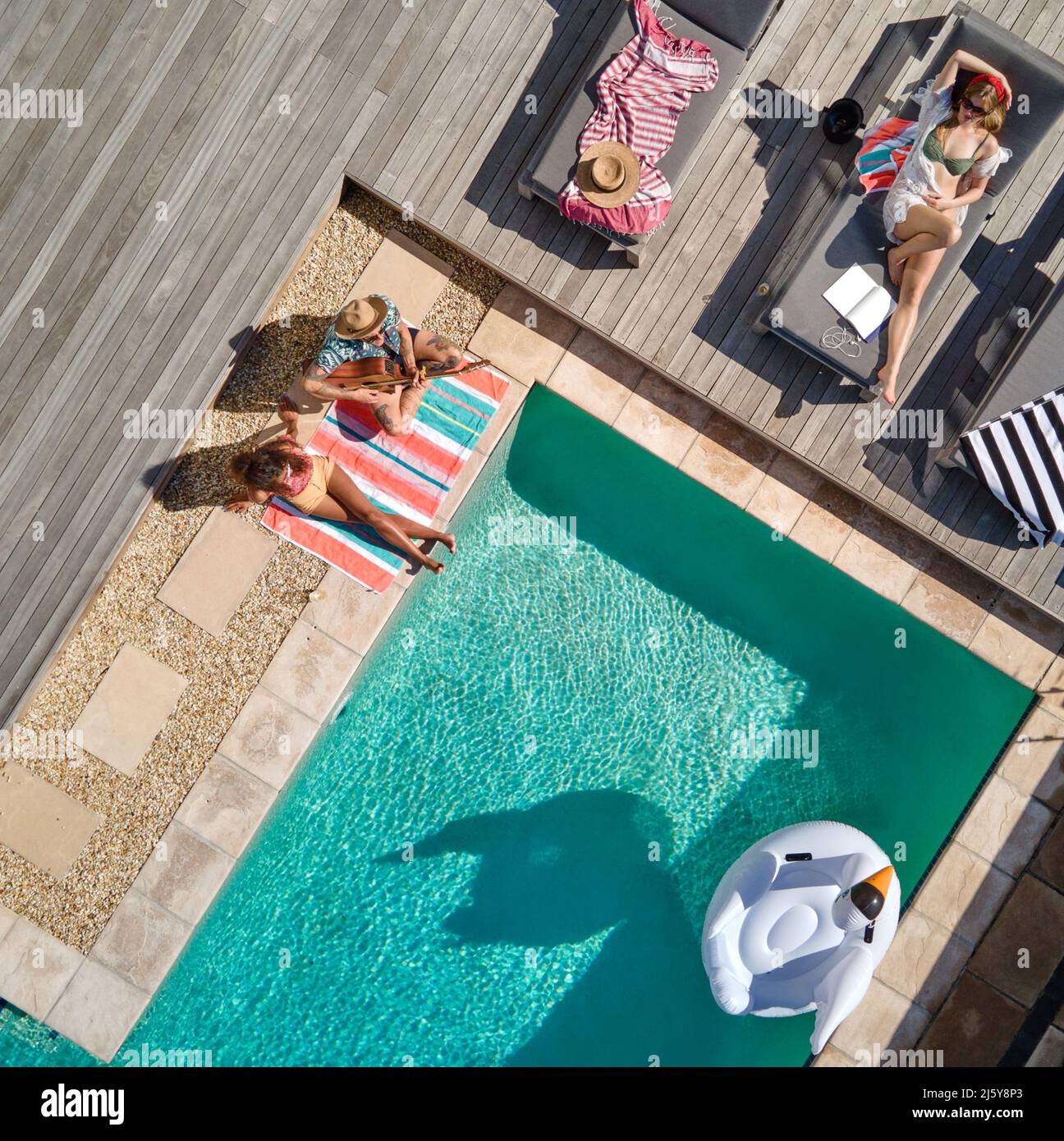 Aerial view friends relaxing at sunny summer poolside Stock Photo