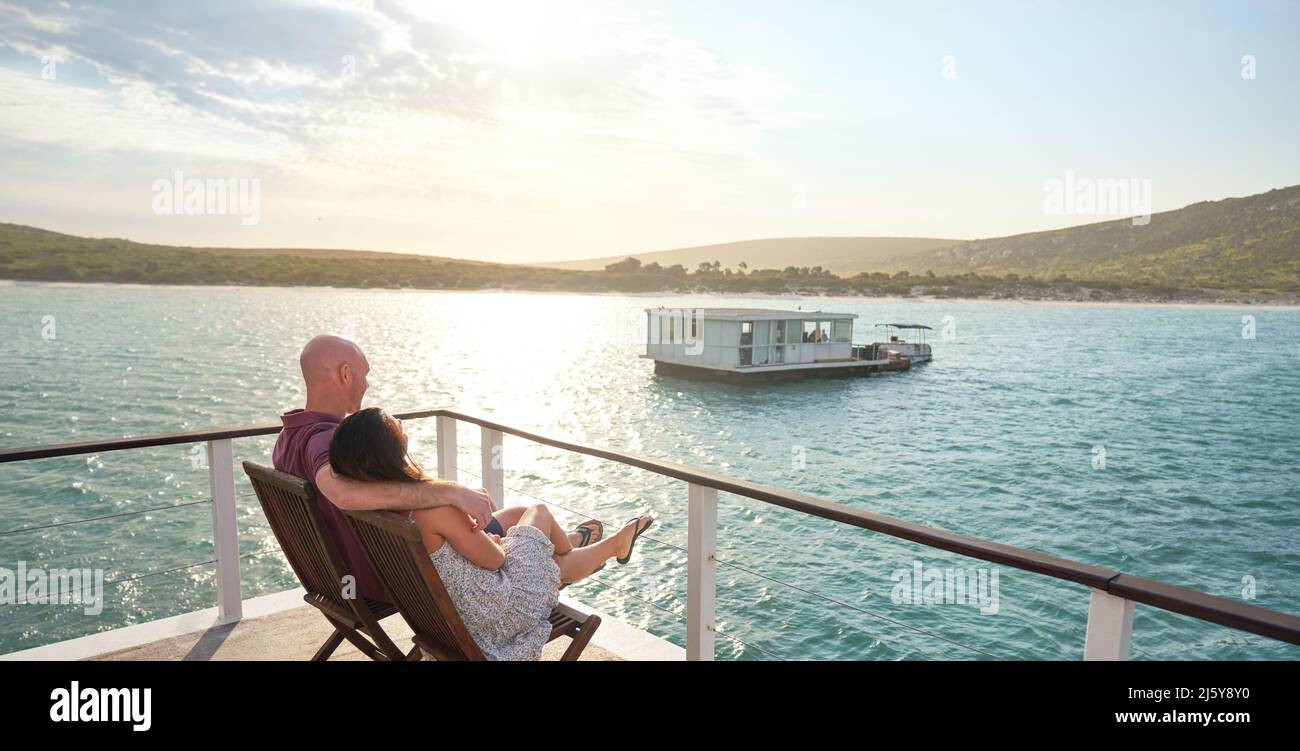 Carefree couple relaxing on houseboat patio on sunny summer lake Stock Photo