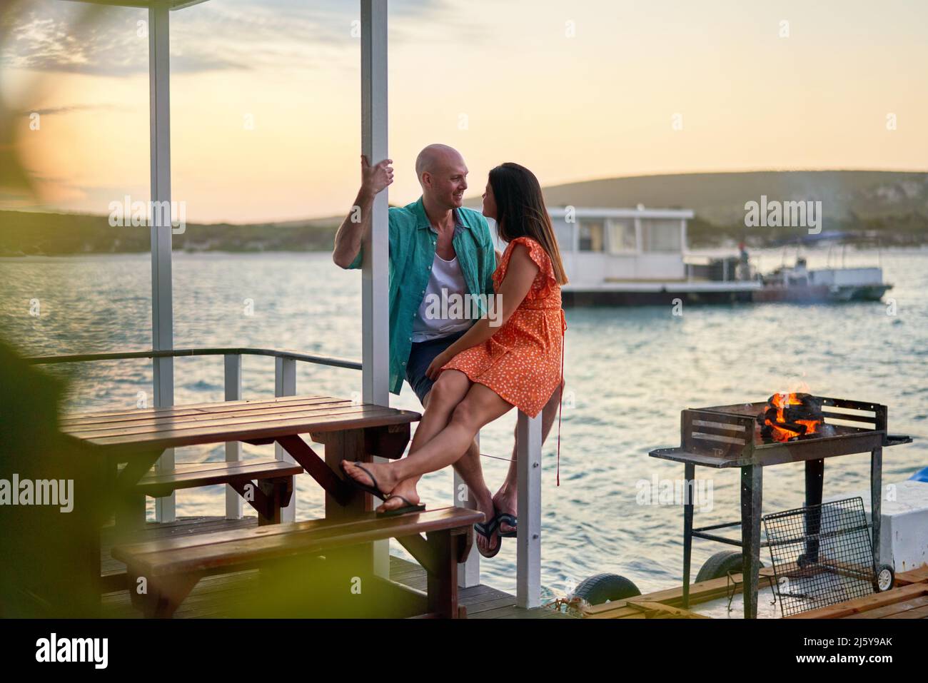 Happy couple relaxing and talking on houseboat patio on lake Stock Photo