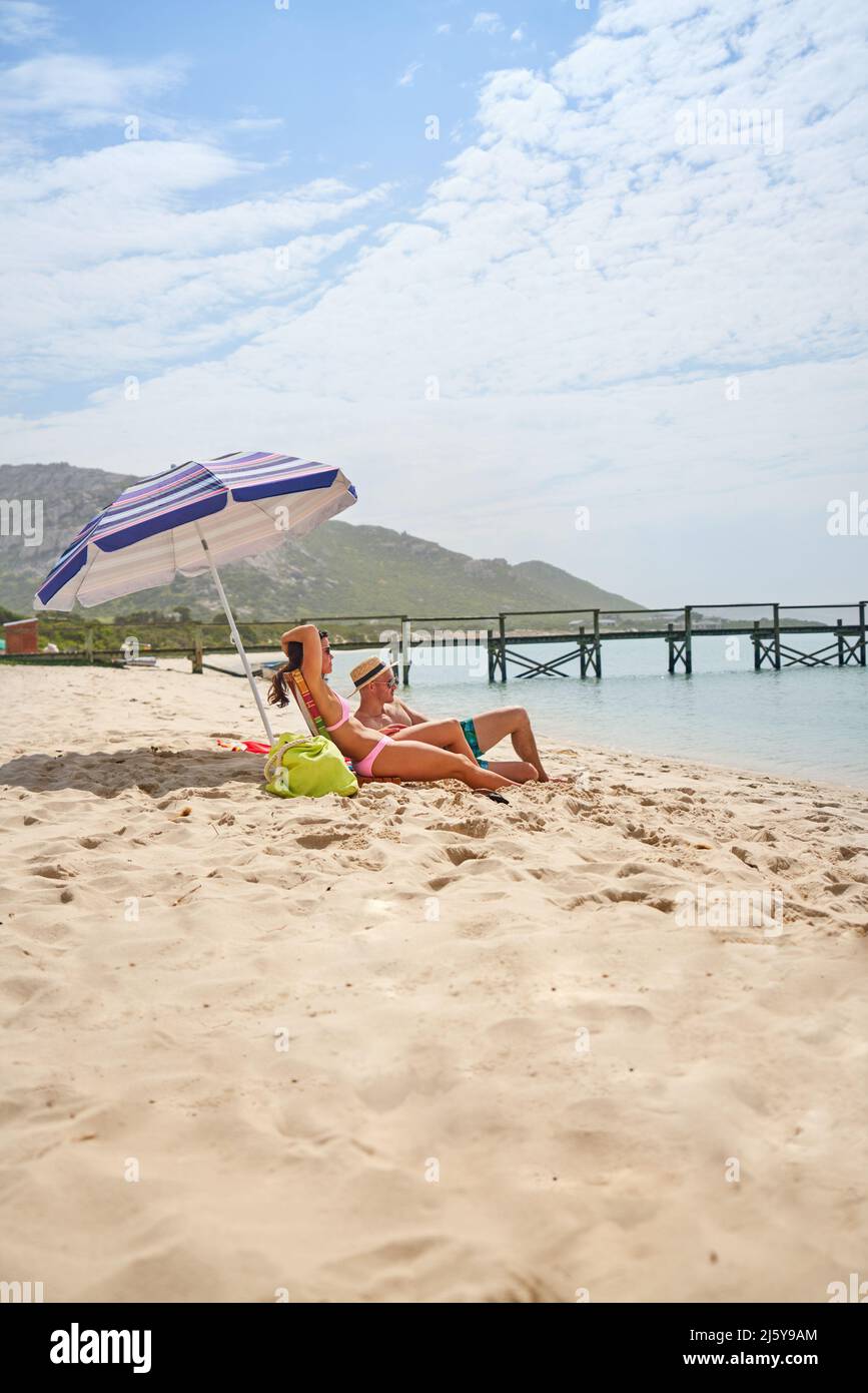 Couple relaxing, sunbathing on ocean beach Stock Photo