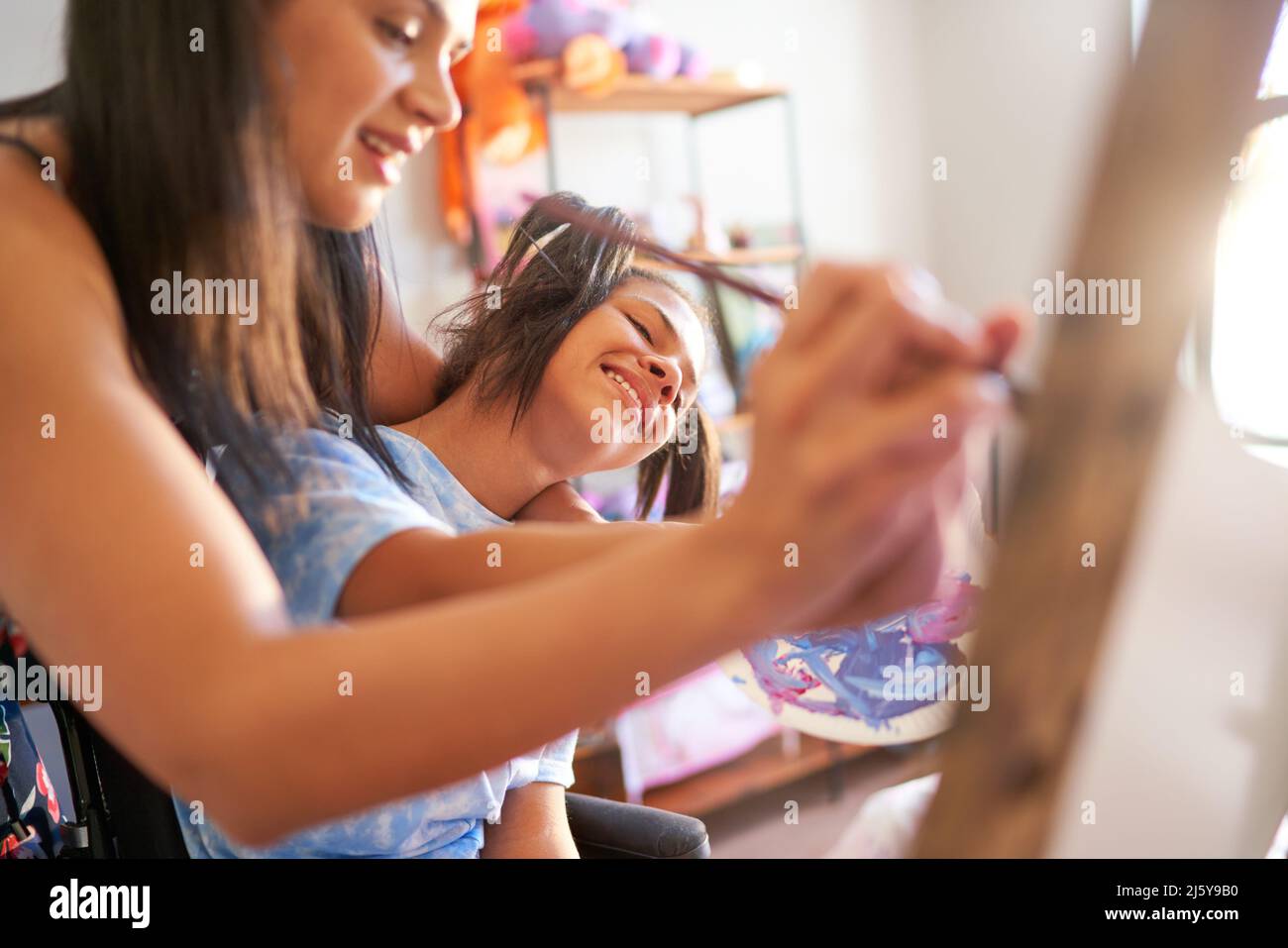 Happy mother and disabled daughter painting together at home Stock Photo