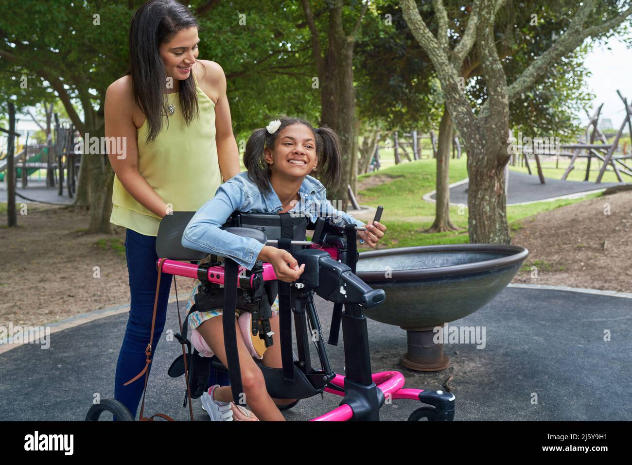 Mother and happy disabled daughter in rollator at park Stock Photo