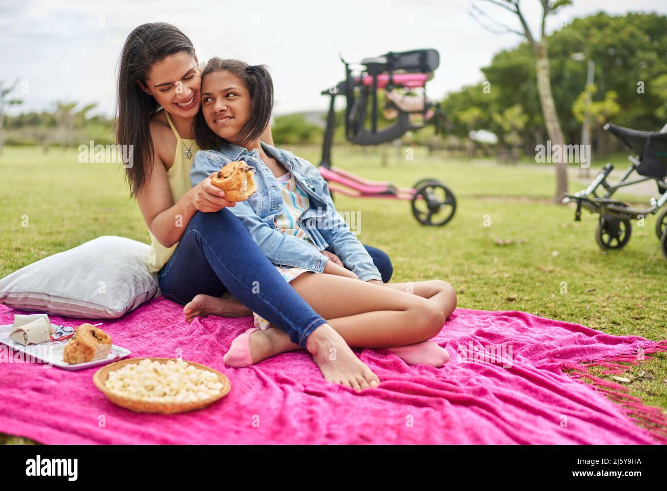 Happy mother and disabled daughter enjoying picnic on blanket in park Stock Photo