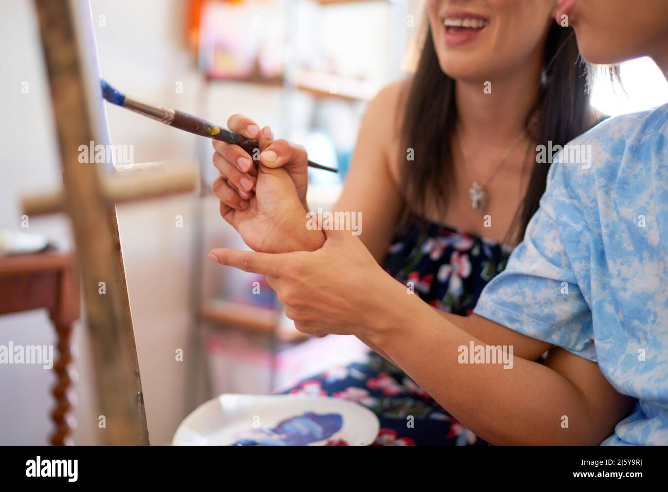 Close up mother helping disabled daughter painting at easel Stock Photo